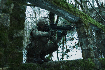 Portrait of airsoft player in professional equipment with machine gun in the forest. Soldier with weapons at war