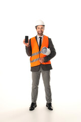 Smiling engineer holding smartphone and blueprint on white background