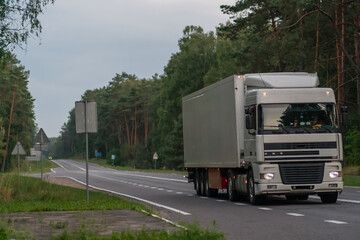Close-up of a white truck on an asphalt road in the forest