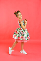 Happy smiling girl with sweets on a pink background, a holiday