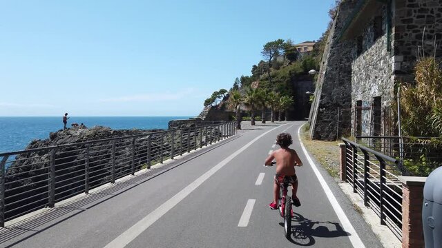 Italy, Spezia, Liguria - The new pedestrian walk , cycle path ( bicycle lane ) that connects Framura, Bonassola and Levanto passing through the ancient train tunnels - 7 years old child go bike