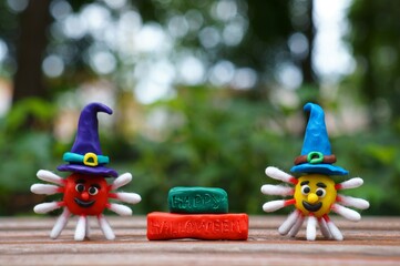 A figure of a virus made of plasticine in a festive hat. Next to the inscription happy Halloween. The concept of Halloween. Close-up.