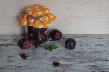 A ripe plum in a jar is lying on the table.