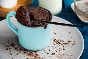 mugcake is microwaved. Homemade cupcake in a mug is on a plate. Chocolate brownie mug cake. Easy...