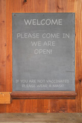 Welcome sign at business on blackboard with mask requirement for covid