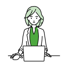 デスクで座ってPCを使っているジャケットの女性