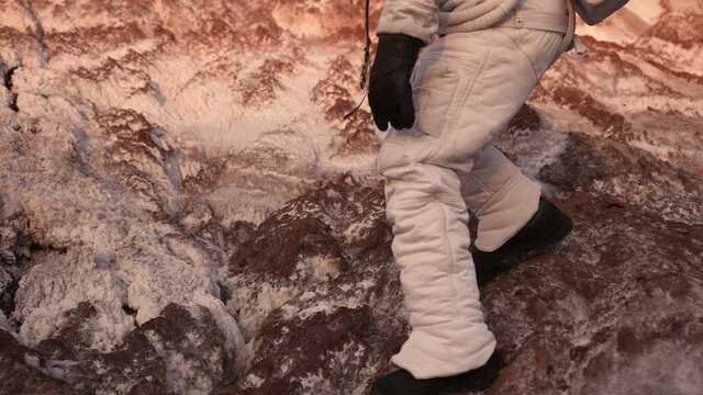 male astronaut is walking on an unknown planet. the astronaut walks cautiously on the surface of the planet. discovery of a new planet. steps on a new planet. walk on the rocks