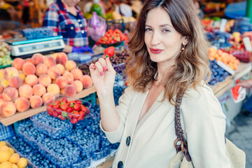 Portrait of middle age pregnant woman enjoy shoping, shoosing berries, holding holding strawberry in eco friendly farmer market. Zero waste concept. New alternative concept.