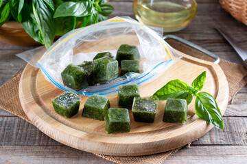 Frozen basil leaves (basilius) in ice cubes with fresh basil on a wooden table. Frozen food concept