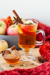Homemade hot fruit tea with fresh apples, honey, spices: cinnamon, cardamon, anise, clove. Warm autumn drink, delicious healthy beverage. Mulled wine. Cozy fall home atmosphere. Wooden background