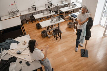 Overhead view of interracial designers talking near mannequin in studio