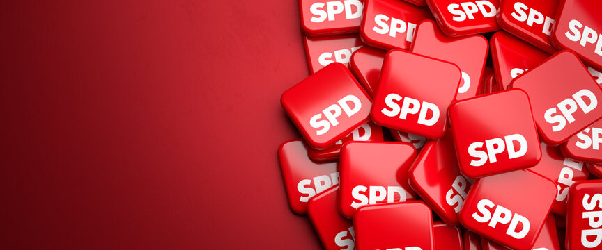 Logos of the center left German political party SPD on a heap on a table. Copy space. Web banner format.