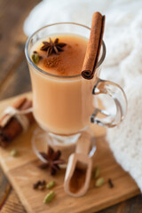 Traditional homemade indian masala chai tea  with ingredients. Cinnamon, cardamon, anise, black tea. Hot autumn and winter drink. Aromatherapy, cozy home atmosphere. Wooden background.