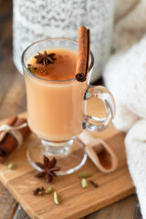 Traditional homemade indian masala chai tea  with ingredients. Cinnamon, cardamon, anise, black tea. Hot autumn and winter drink. Aromatherapy, cozy home atmosphere. Wooden background.