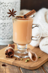 Obraz na płótnie Canvas Traditional homemade indian masala chai tea with ingredients. Cinnamon, cardamon, anise, black tea. Hot autumn and winter drink. Aromatherapy, cozy home atmosphere. Wooden background.