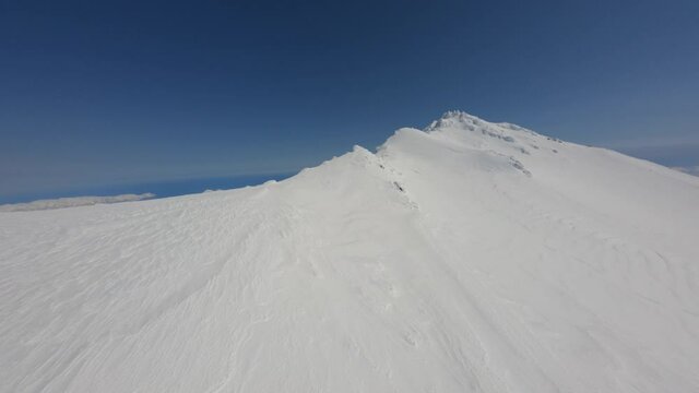 Clear wilderness environment mountain scenery iced summit at nature landscape at sunny winter day aerial view. Fpv sport drone shot beautiful sharp winter cliff epic surrounded by endless blue sky