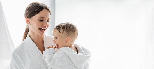amazed mother looking at toddler son in bathrobe, banner