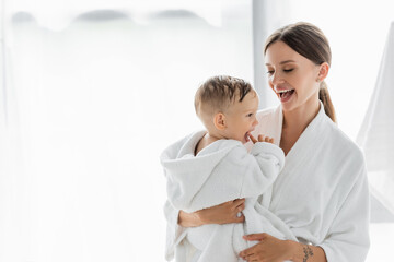 amazed mother looking at toddler son in bathrobe