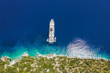 Aerial top down view of luxury lonely yacht boat in turquoise blue sea on secluded remote coast of Kefalonia Ionian island, Greece