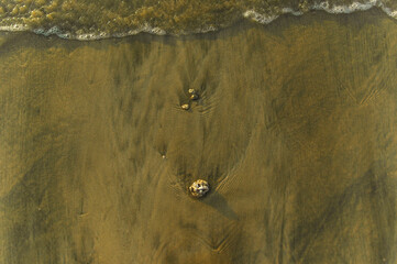 Detail of the ocean with waves and white bubbles and stones