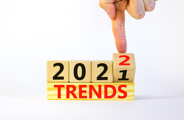 2022 trends new year symbol. Businessman turns a wooden cube and changes words 'Trends 2021' to 'Trends 2022'. Beautiful white background, copy space. Business, 2022 trends new year concept.