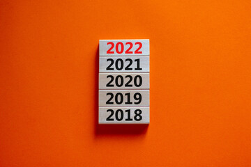2022 happy new year symbol. Wooden block with number '2022'. Stack with numbers '2018, 2019, 2020, 2021'. Beautiful orange background. Copy space. Business, 2022 happy new year concept.