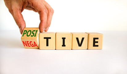 Positive or negative symbol. Businessman turns a wooden cube, changes the word 'negative' to 'positive'. Beautiful white table, white background, copy space. Business, positive or negative concept.