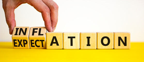 Inflation and expectation symbol. Businessman turns cubes, changes the word inflation to expectation. Beautiful yellow table, white background, copy space. Business, inflation and expectation concept.
