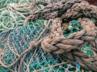 Old and unraveled fishing ropes and nets grouped together for review before the fishermen set out to fish forming an abstract background marin