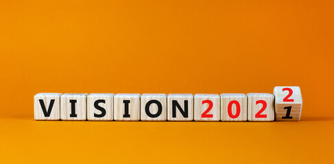 2022 vision new year symbol. Turned a wooden cube and changed words 'vision 2021' to 'vision 2022'. Beautiful orange background, copy space. Business, 2022 vision new year concept.