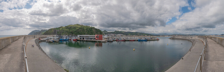 Fototapeta na wymiar Overview of the fishing port of Laredo with the boats docked next to the San Martín fishermen's association and the marina and the village in the background