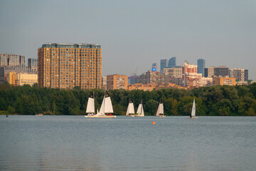 Yachts sail against the background of evening Moscow.