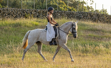 Riding white Lusitano horse, outdoors on grass, cute team, trotting.