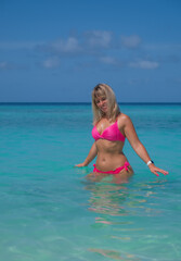 Fototapeta na wymiar Beautiful blond woman in pink bikini by blue lagoon. Crossroads Maldives, indian ocean. Saii lagoon hotel, july 2021