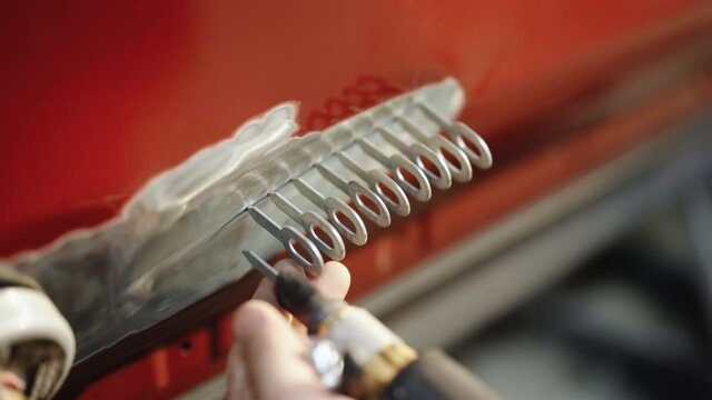 Car repair shop, pulling out dents. Professional auto workshop worker dented door of car. Mechanic repair car body