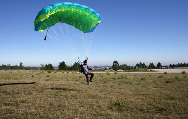 Skydiver landing his parachute on the ground - obrazy, fototapety, plakaty
