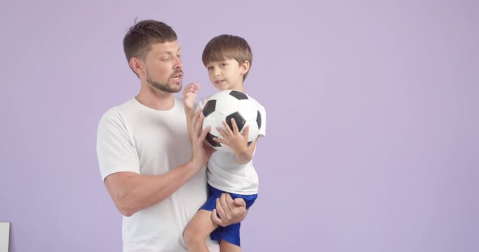 Coach teaching little boy how to play soccer against color background