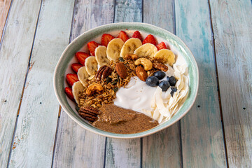 Great bowl of nuts and fresh fruits with yogurt. Flat sliced, pieces of strawberries, walnuts, almonds and cashews, ripe blueberries and coconut slices