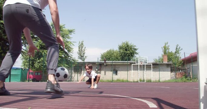 Little boy and his father playing soccer outdoors
