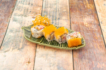 Four pieces of uramaki california roll prawn with nori seaweed and fish roe on leaf-shaped plate