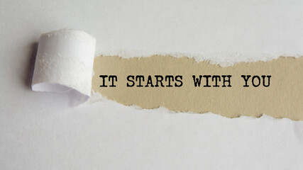 IT STARTS WITH YOU. words. text on grey paper on torn paper background
