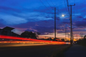 Fototapeta na wymiar Paisaje urbano con el trafico en forma de haces de luces de fondo, tomada con larga exposición con destaques en azul, rojo y naranja 