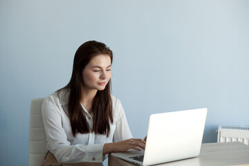 young beautiful girl in office clothes works on a laptop