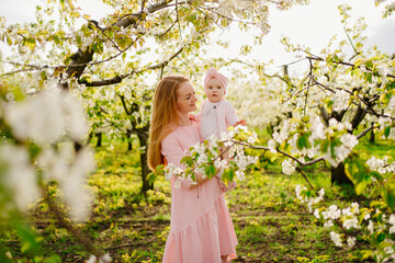 mother with baby in arms in flowering garden. surgery for child with cleft lip.