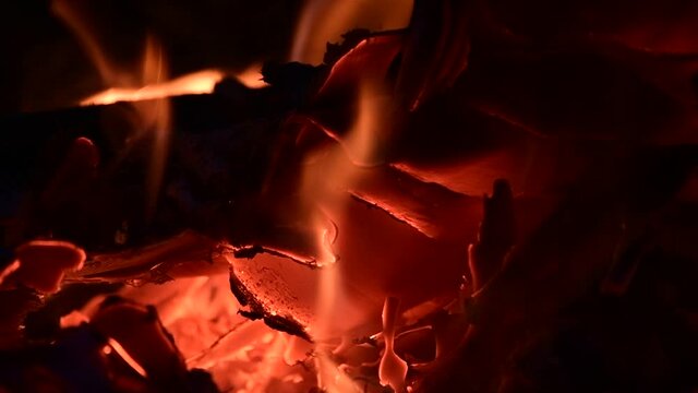 Close-up of a burning campfire, night bonfire, logs, plywood and fabriv are on fire, gust sparks fly, slo-mo HD video