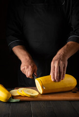 The cook cuts ripe yellow marrow with a knife. Fried zucchini is a great diet for breakfast or lunch. Work environment on the kitchen table of the restaurant