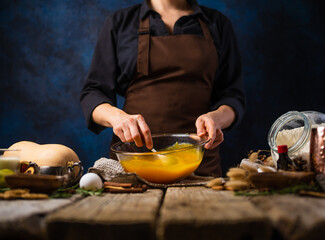 The chef is stirring the pumpkin filling for the pumpkin pie. A traditional American cake for all celebrations and events. Lots of ingredients. Close-up. Restaurant, hotel, pastry shop.