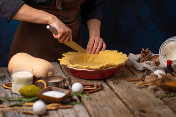 The chef puts the prepared dough into a baking dish. Cooking pumpkin pie. Lots of ingredients. Wooden texture. Country style. Advertising, booklet, poster, menu design.