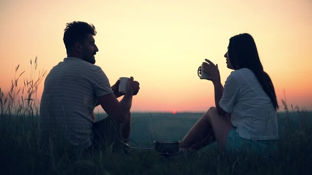 The man and woman drinking tea on the beautiful sunset background