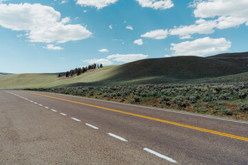 Fototapeta na wymiar Empty asphalt road with hills and blue sky in Montana